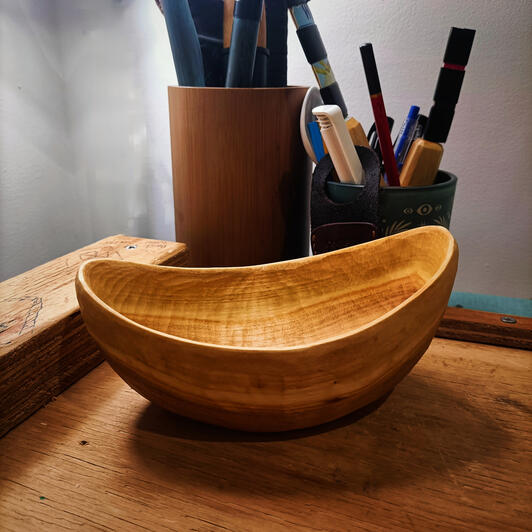 hand carved cherry bowl a bowl sits on a workspace alongside pots of various craft items